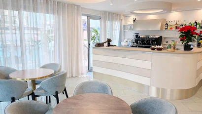 Hotel Regal: comfort ed eleganza a Rimini Interno di un caffè moderno con tavoli e poltrone grigie e bancone bar bianco