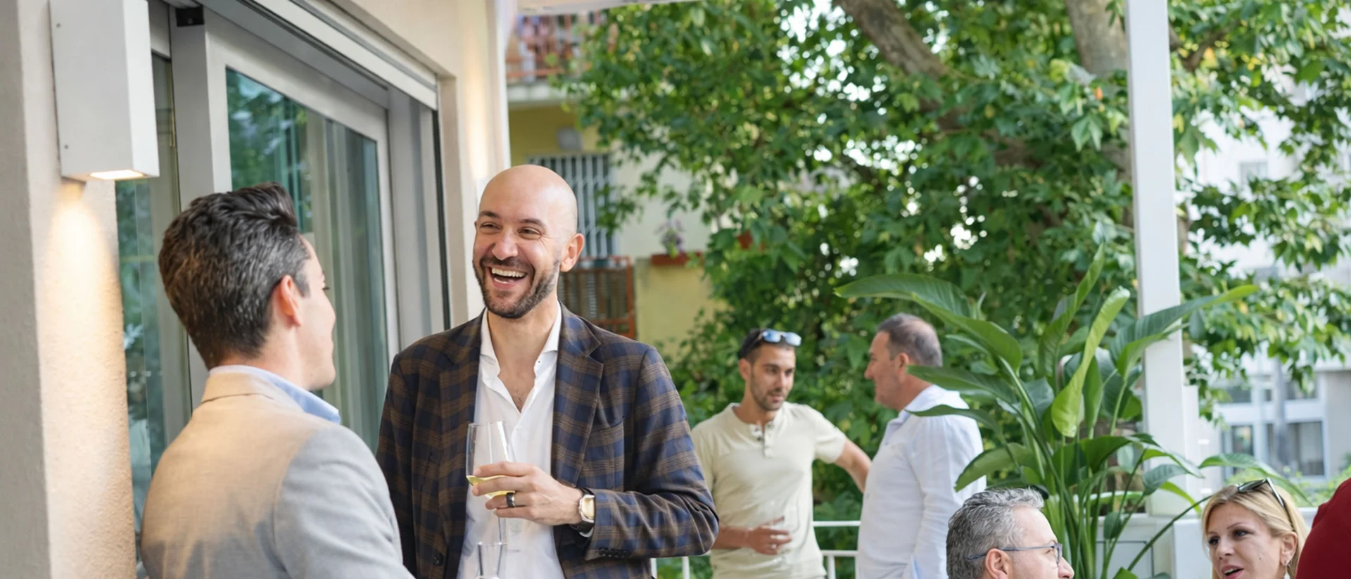 Hotel Regal: comfort ed eleganza a Rimini Persone che socializzano e bevono su un balcone esterno con piante e alberi